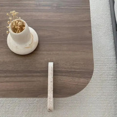 Wooden desk with a small vase and plant on top, next to a gray carpet.
