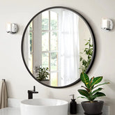 Bathroom with round mirror, sink, and plant