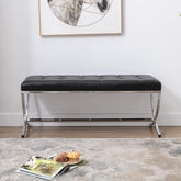 Black tufted bench with chrome legs in a room setting with a rug and magazine.