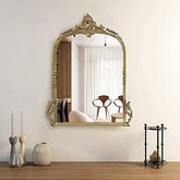 Decorative gold mirror on a wall with a room reflection