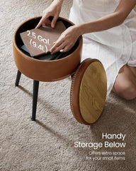 Person placing a container into a round brown stool with wooden top on a carpeted floor.