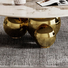 Coffee table with gold metallic base and marble top on a textured floor.