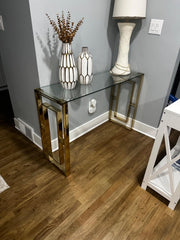 Glass console table with decorative items against a gray wall.