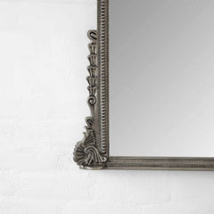 Decorative mirror with intricate frame on a white wall