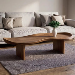 Wooden coffee table in front of a beige sofa with decorative pillows in a living room setting.