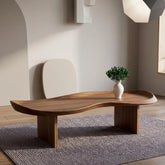 Wooden coffee table with a vase of greenery in a minimalistic room.