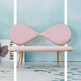 Pink butterfly-shaped bench with gold accents against a light blue wall.