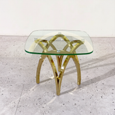 Glass table with gold metal legs on a light gray floor