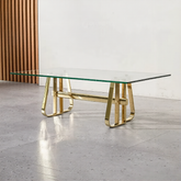 Glass table with gold metal legs on a light gray floor.