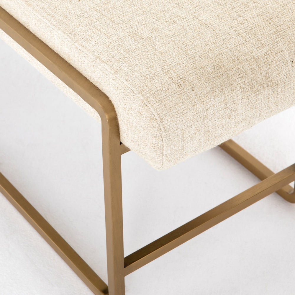 Beige cushioned stool with gold metal frame on a white background