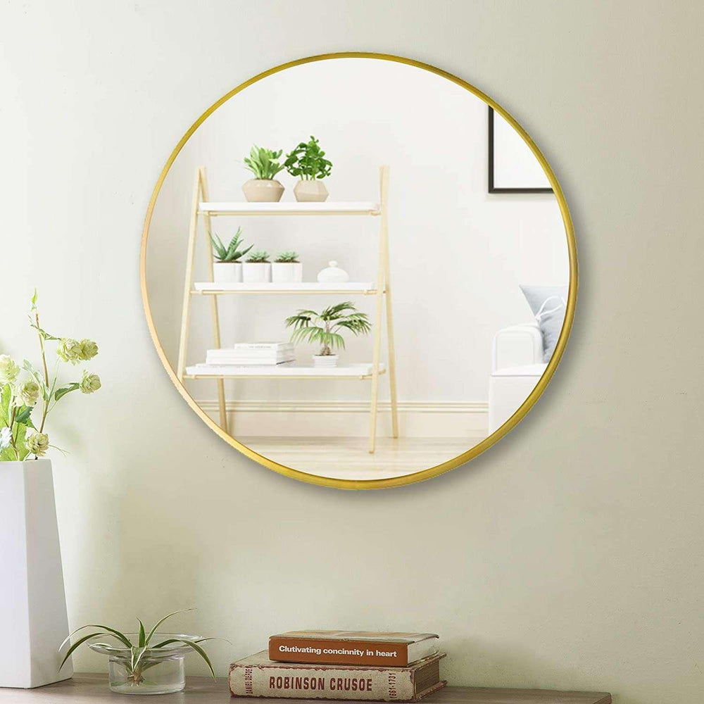 Round gold-framed mirror on a wall with a shelf and plants reflected in it.