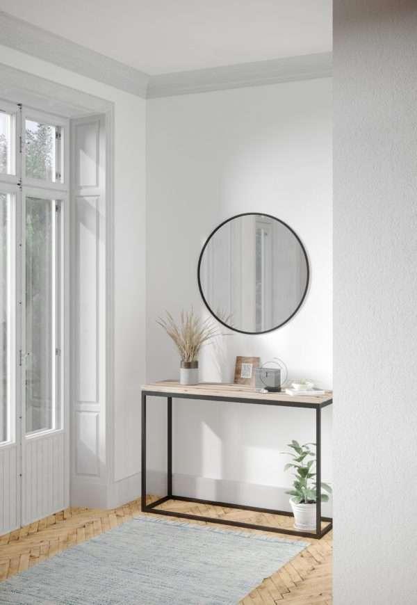 Modern interior with a round mirror, console table, and plants in a minimalistic setting.
