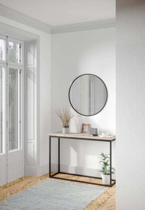 Modern interior with a round mirror, console table, and plants in a minimalistic setting.