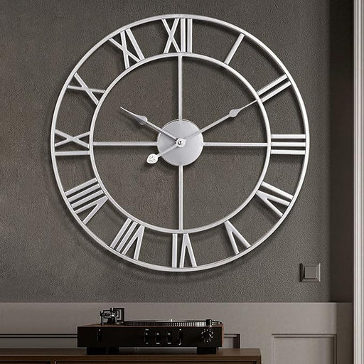 Large wall clock with Roman numeral markers on a gray wall.
