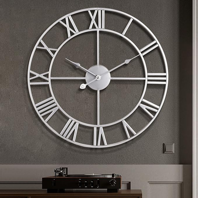 Large wall clock with Roman numeral markers on a gray wall.