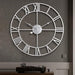 Large wall clock with Roman numeral markers on a gray wall.