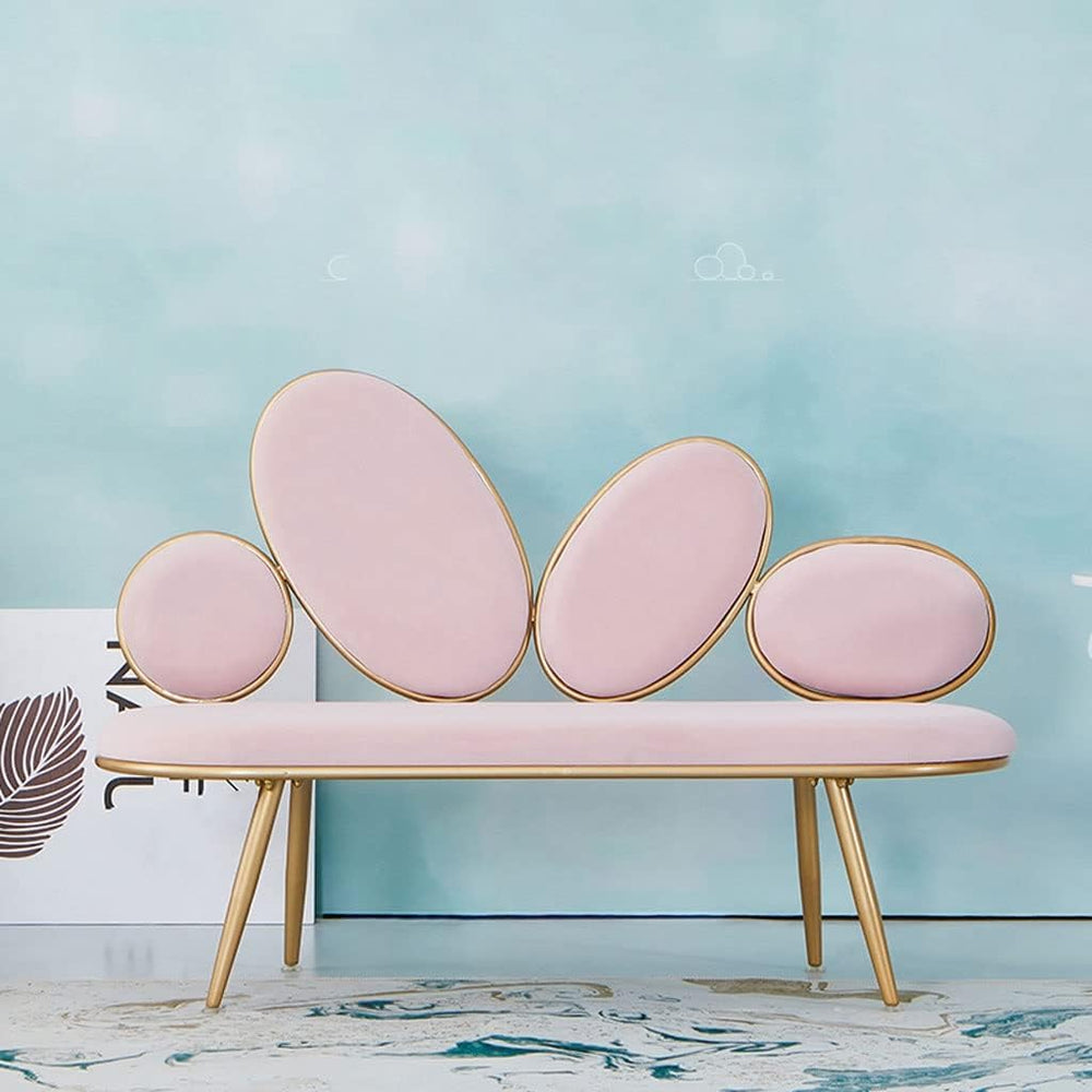 Pink bench with gold legs against a light blue wall