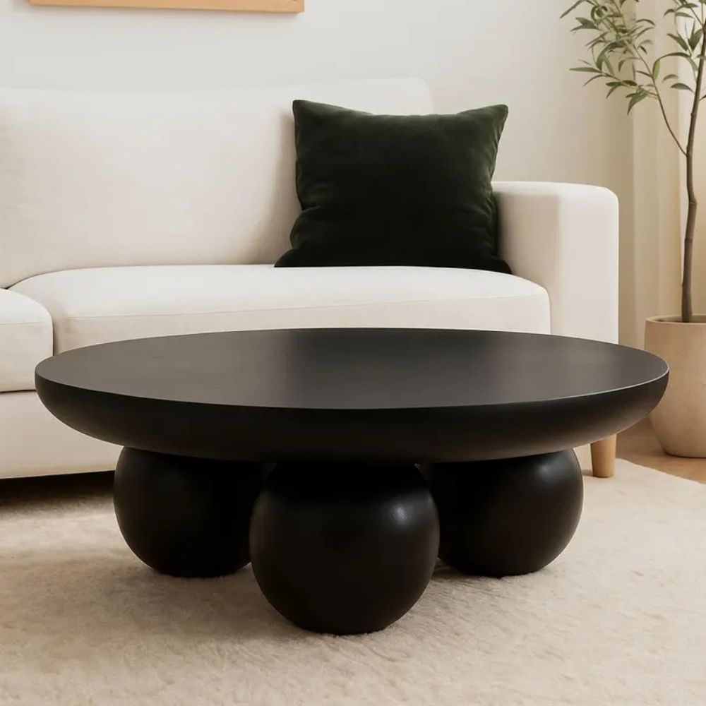 Black coffee table with spherical bases in a living room setting