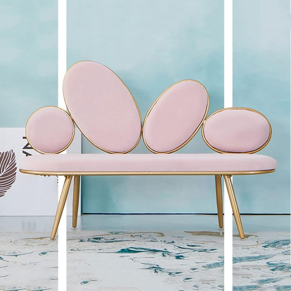 Pink bench with gold accents against a light blue wall