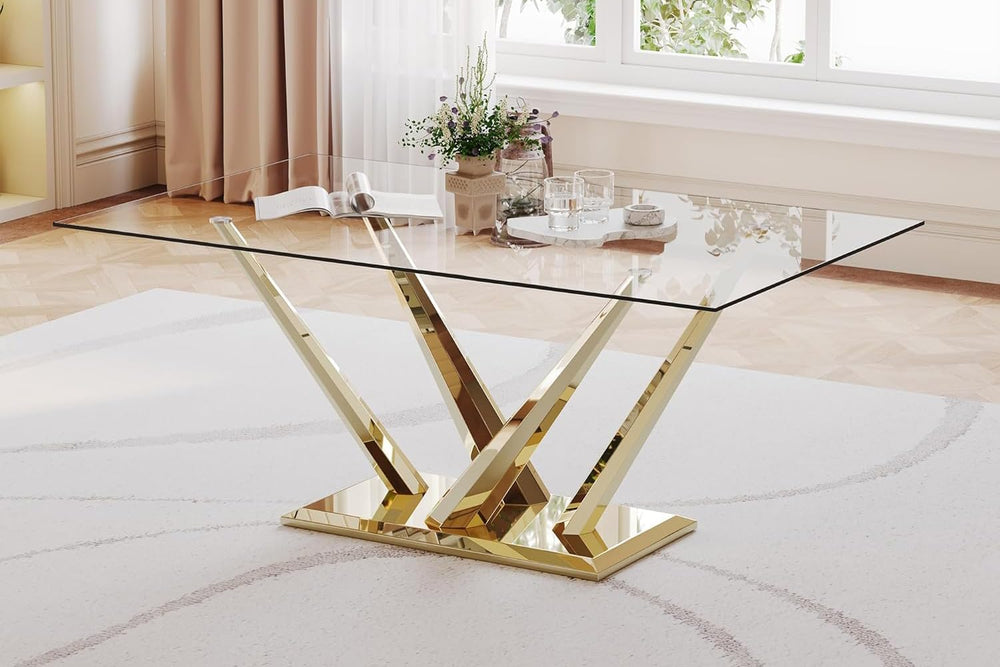 Glass dining table with gold metal legs in a room with light wood flooring and curtains.