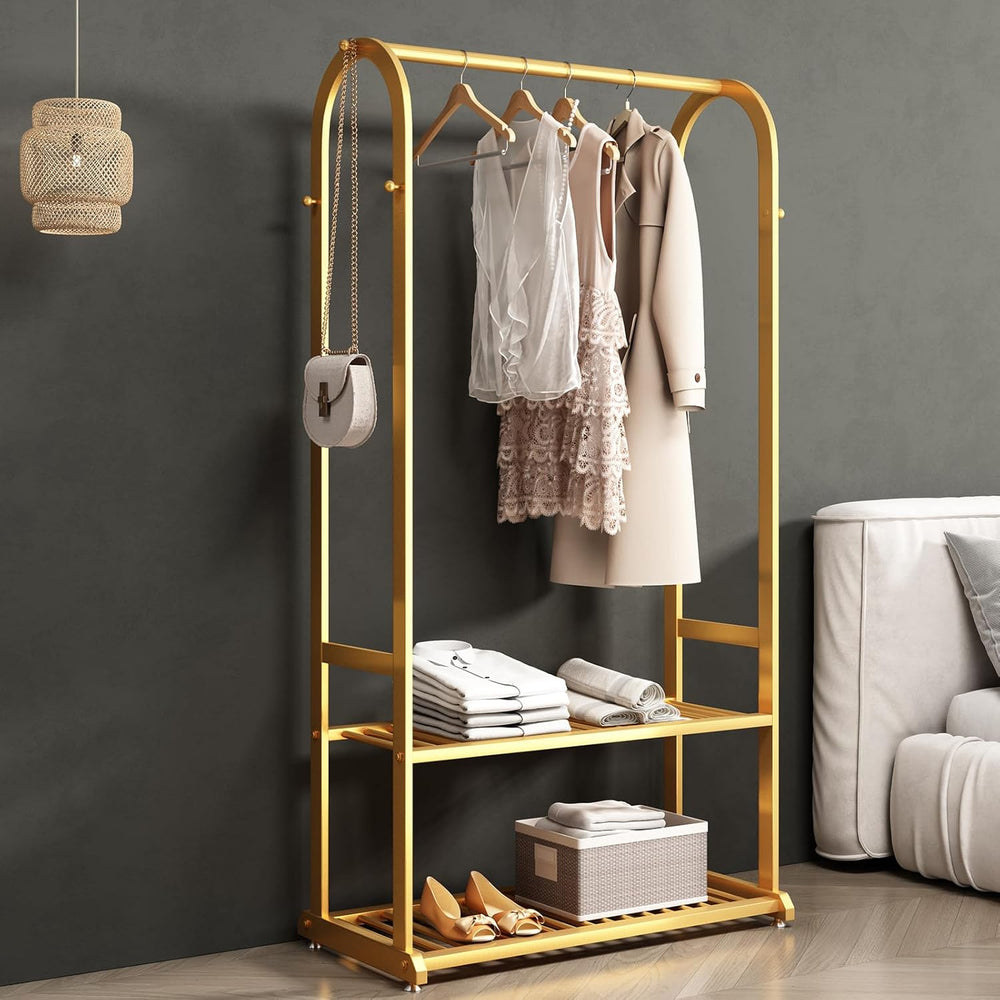 Gold clothing rack with clothes and shoes against a gray wall.