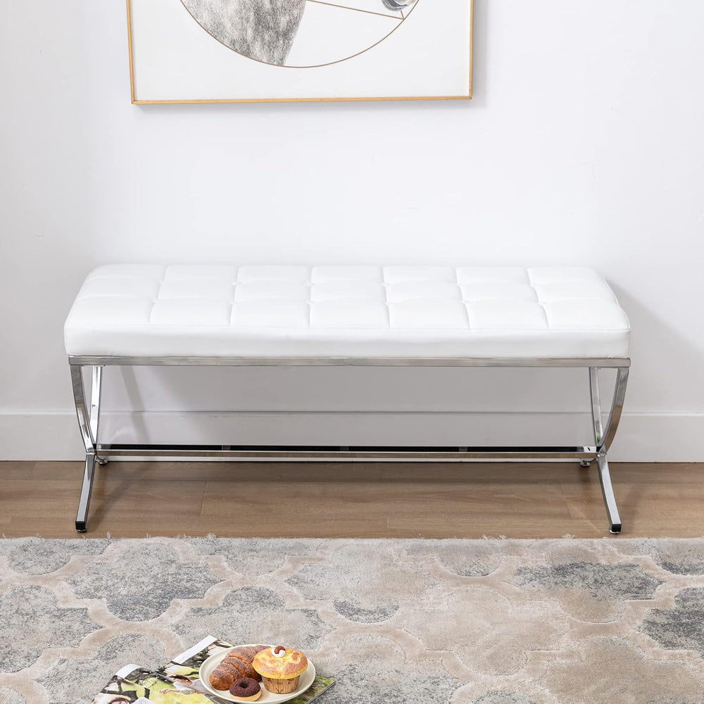 White bench in a room with a rug and framed picture on the wall.