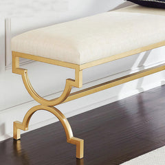 Gold bench with white cushion on a dark wooden floor