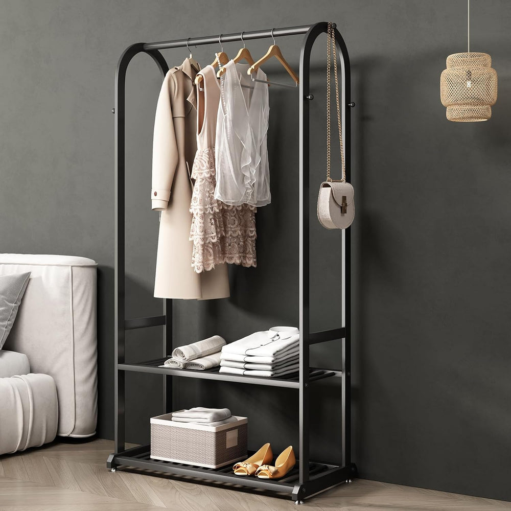 Black clothing rack with clothes and shoes against a gray wall.