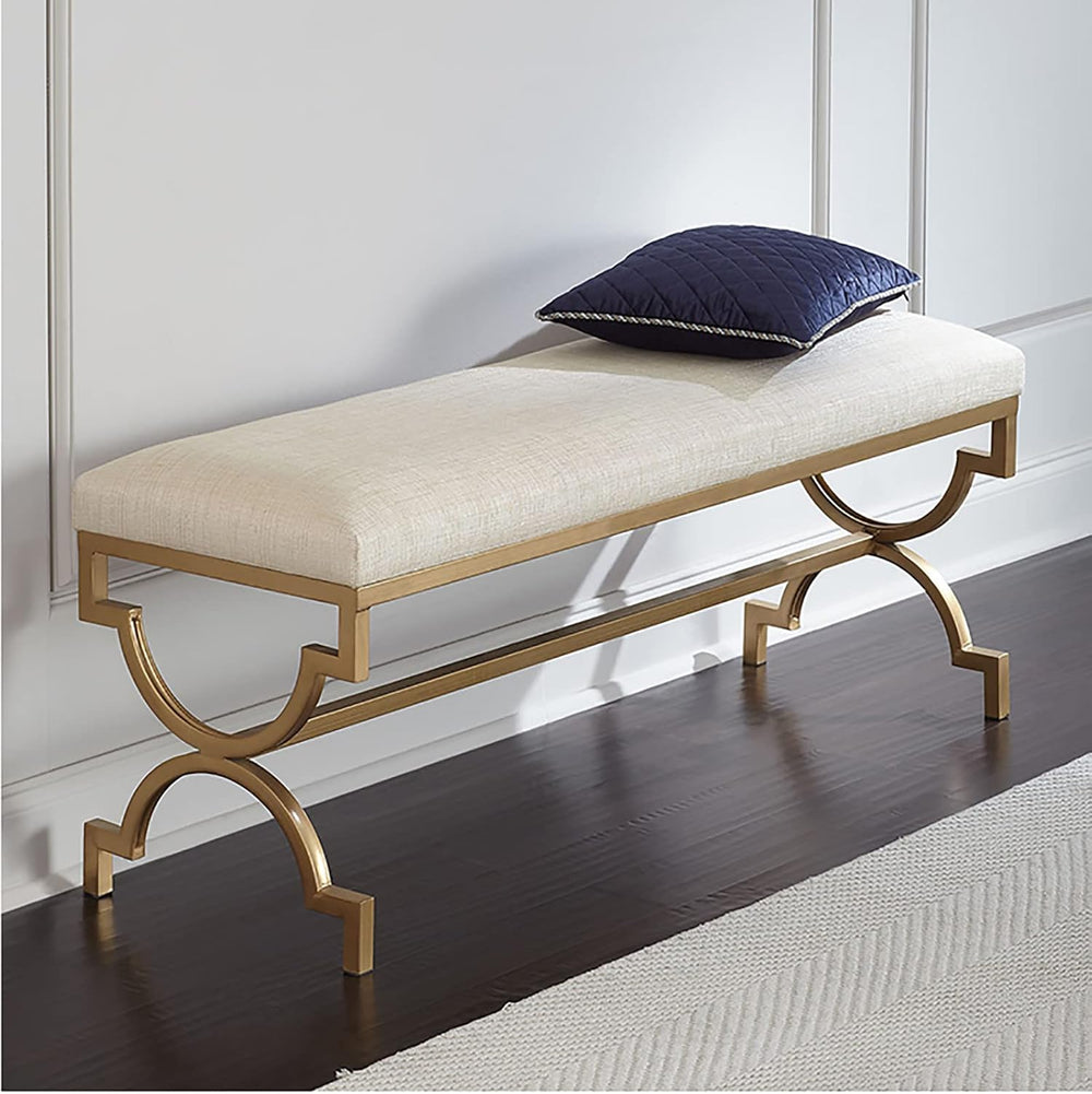 Decorative bench with gold legs and white cushion on a dark wooden floor.