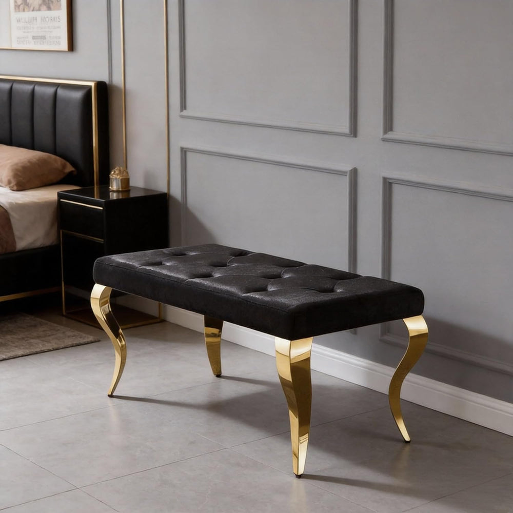 Black tufted bench with gold legs in a bedroom setting