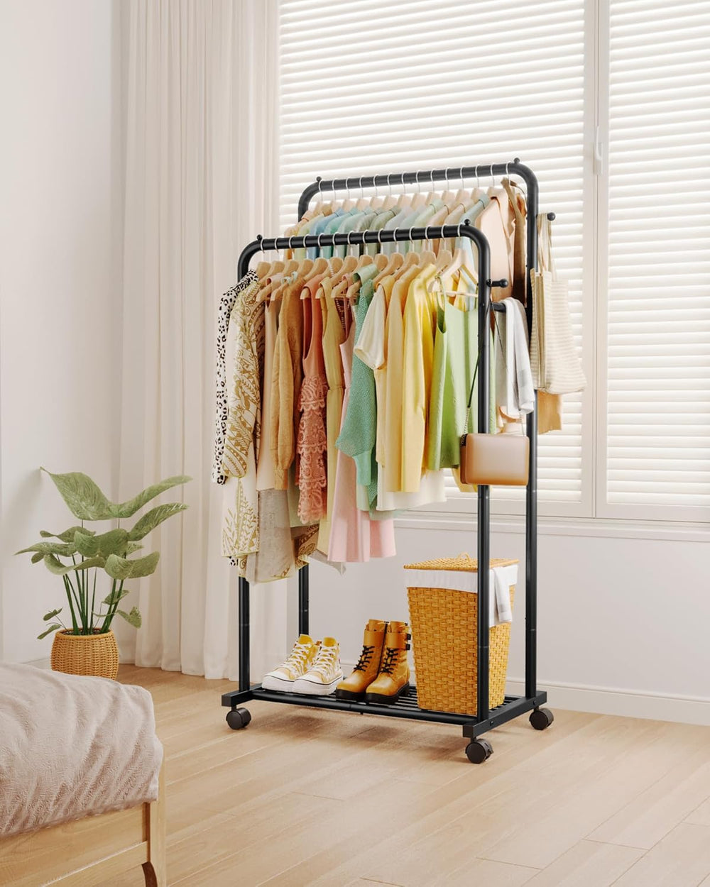 Clothing rack with clothes in a room with a plant and window blinds.