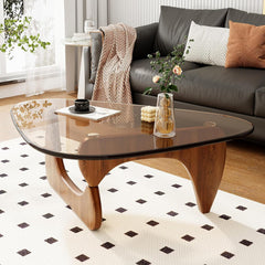 Modern living room with a glass coffee table, gray sofa, and decorative items.