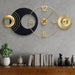 Decorative wall clock with geometric design on a gray wall above a wooden shelf.