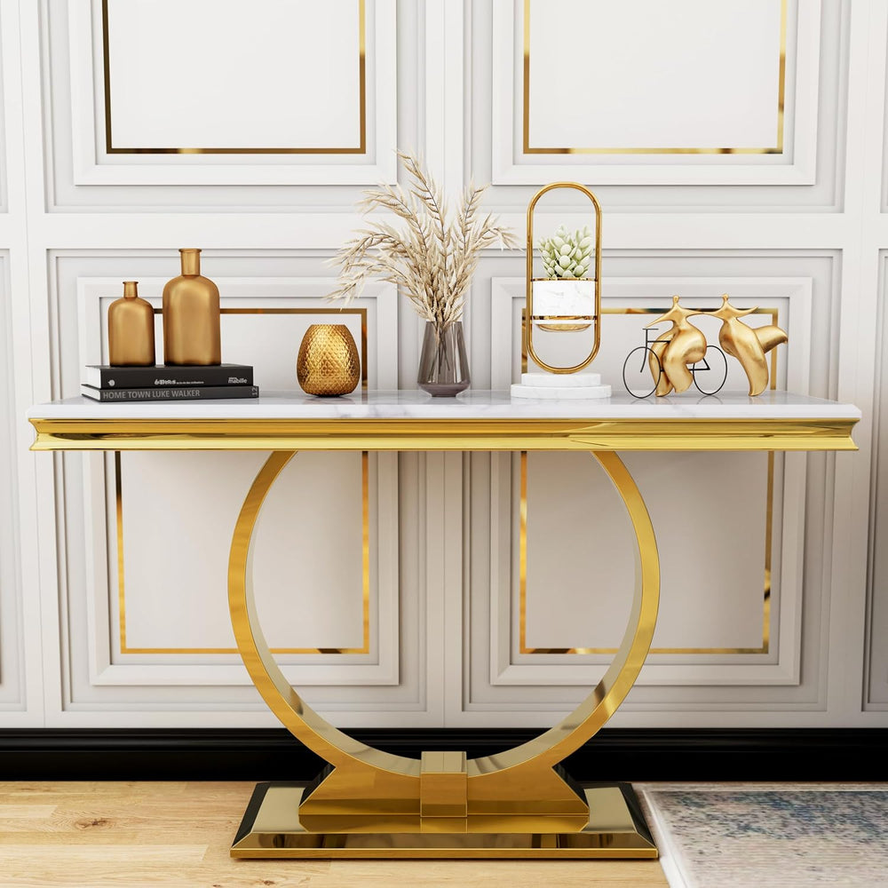 Gold console table with decorative items against a white wall with gold frames