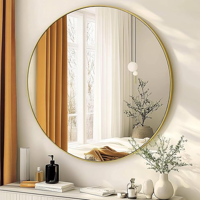 Round gold-framed mirror on a wall with decorative items below