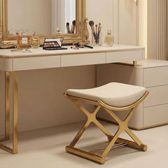 Dressing table with mirror, makeup items, and a stool in a room setting.
