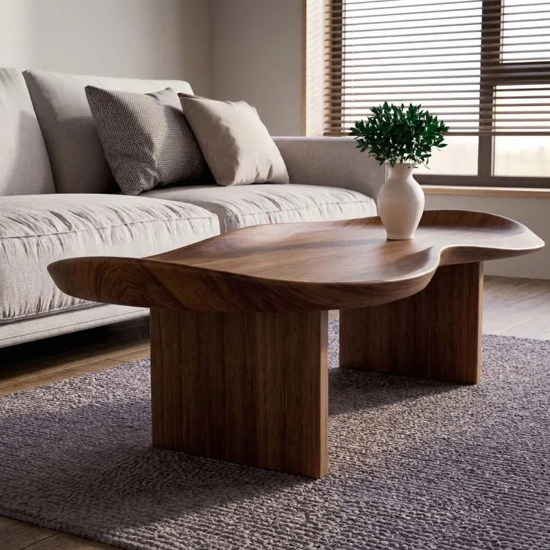 Wooden coffee table in a living room with a sofa and decorative plant.