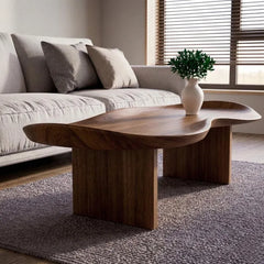 Wooden coffee table in a living room with a sofa and decorative plant.
