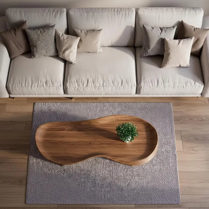 Beige sectional sofa with decorative pillows and a wooden coffee table on a rug.