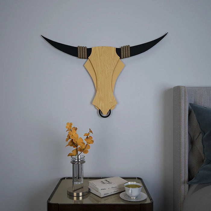 Wooden bull head wall decoration on a plain wall with a small table and decorative items below.