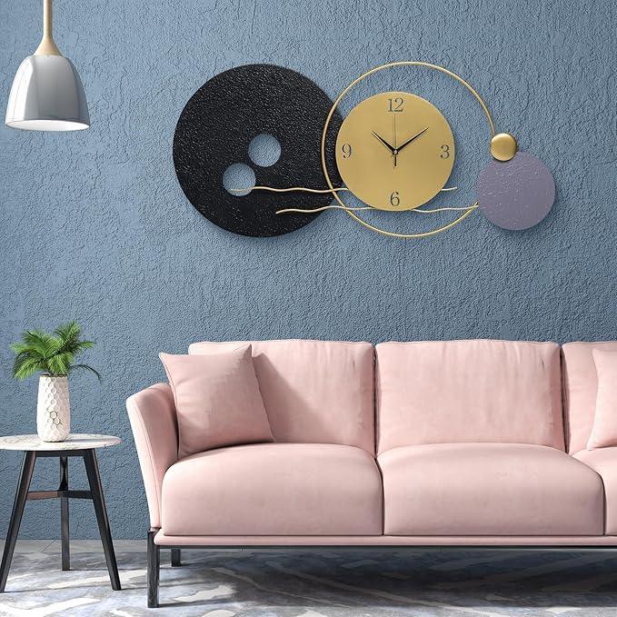Modern living room with a pink sofa, decorative wall clock, and small table with a plant.