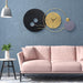 Modern living room with a pink sofa, decorative wall clock, and small table with a plant.