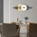 Modern wall clock with decorative design in a room with a table and chairs.
