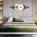 Decorative wall clock with moon and star design above a bed in a bedroom.