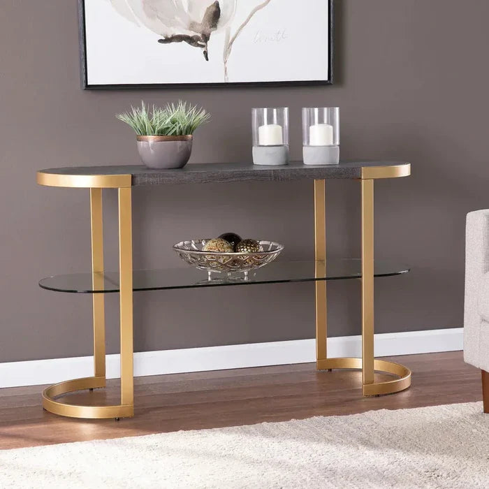Console table with gold legs and glass shelves in a room setting.