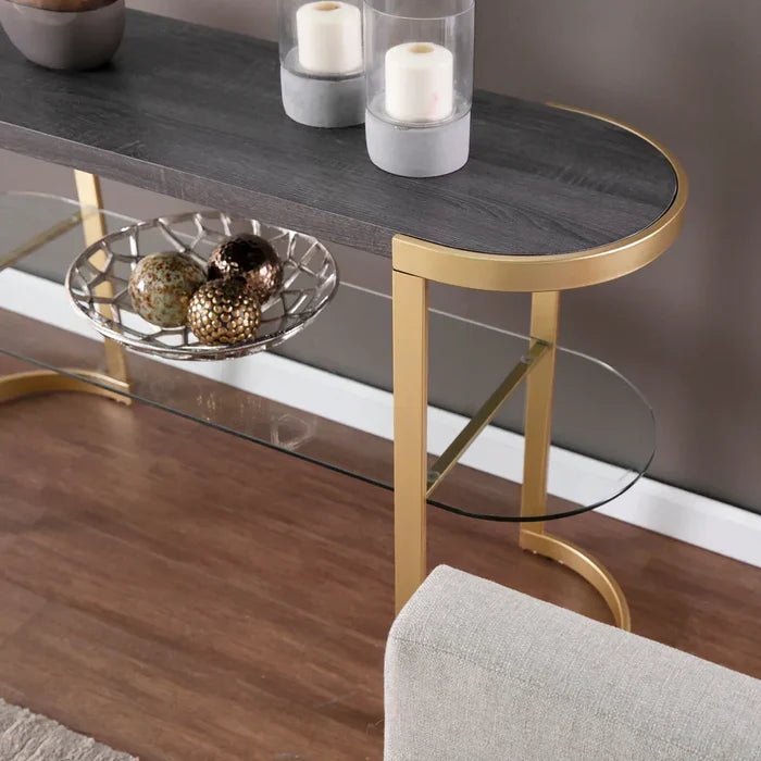 Console table with gold legs and dark surface, featuring decorative items on a wooden floor.