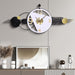 Decorative wall clock with black, gold, and white design on a gray wall.