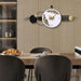 Modern wall clock with decorative elements on a wall above a dining table.
