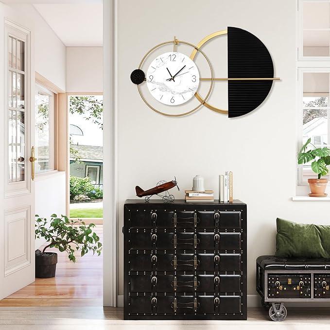 Modern wall clock with black and gold design on a white wall above a black cabinet.