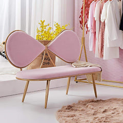 Pink bench with gold frame in a room with clothes rack and plant